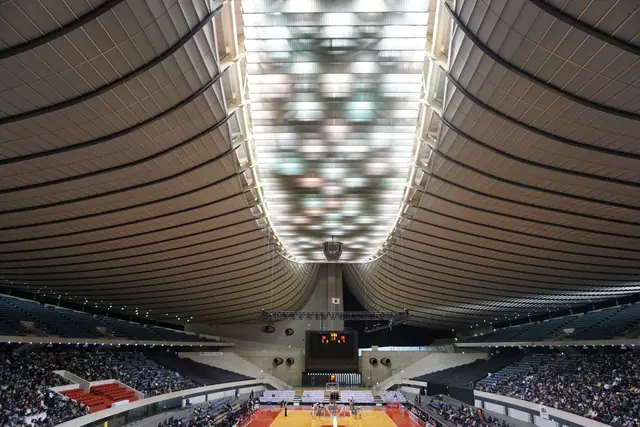 The curved roof and lights of an indoor basketball arena