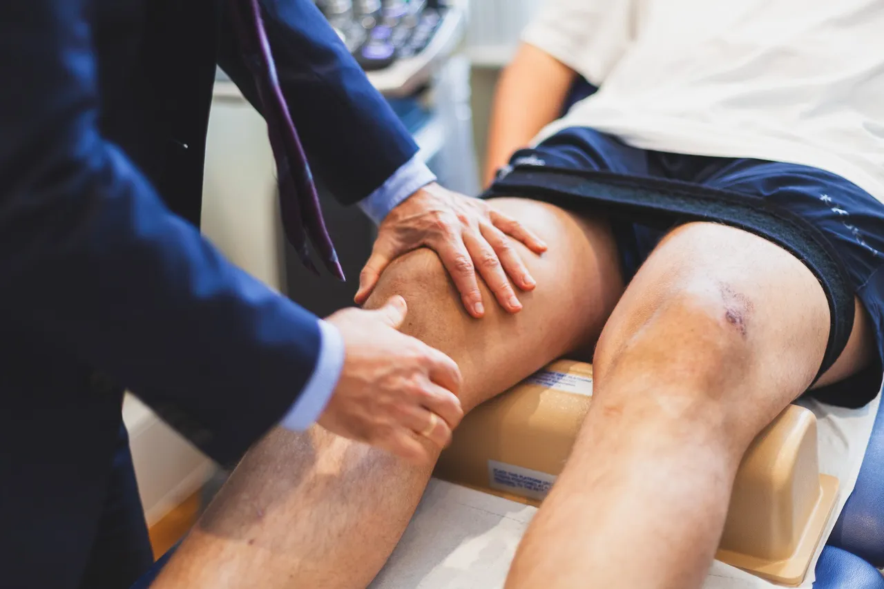A sports medicine clinician examines an athlete's knee with both hands during an assessment.