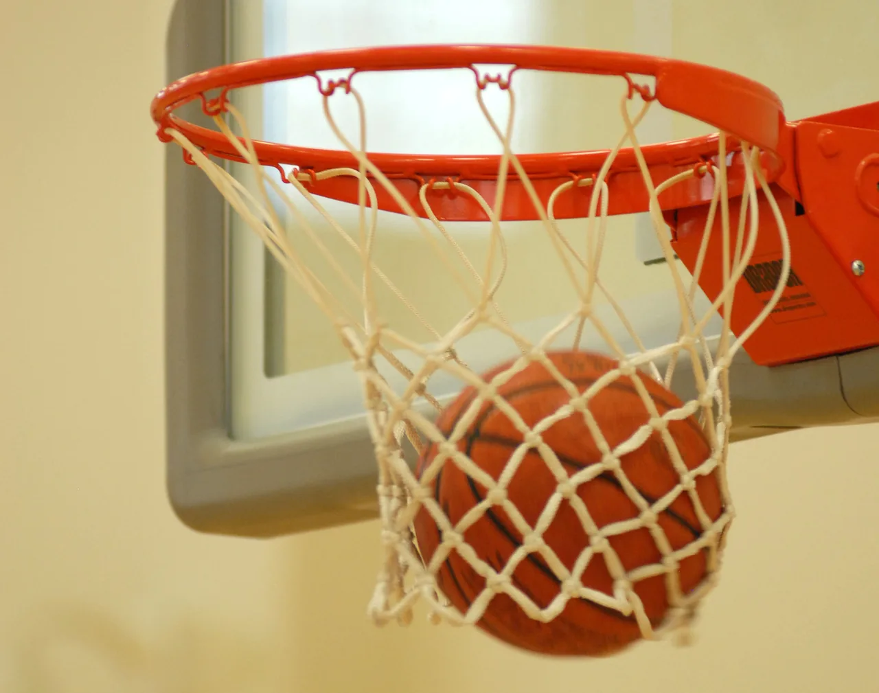 A basketball dropping through an orange rim and white net