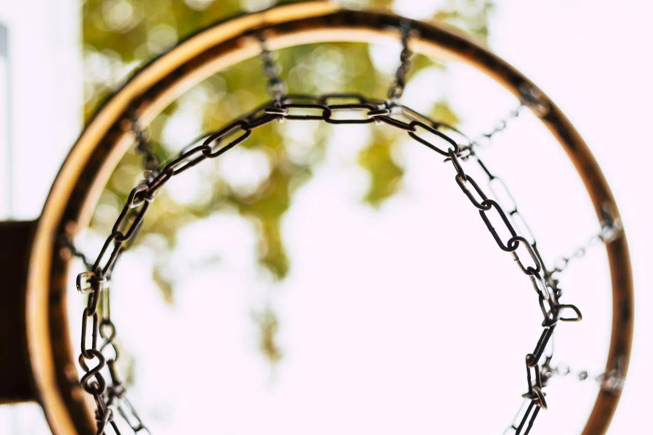 A chain net on a street court rim, seen from below