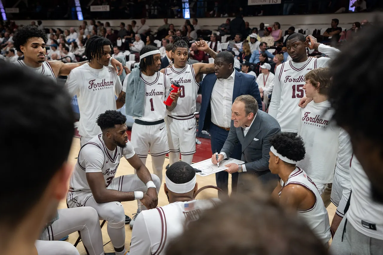 A college head coach sketches a play on a whiteboard during a timeout