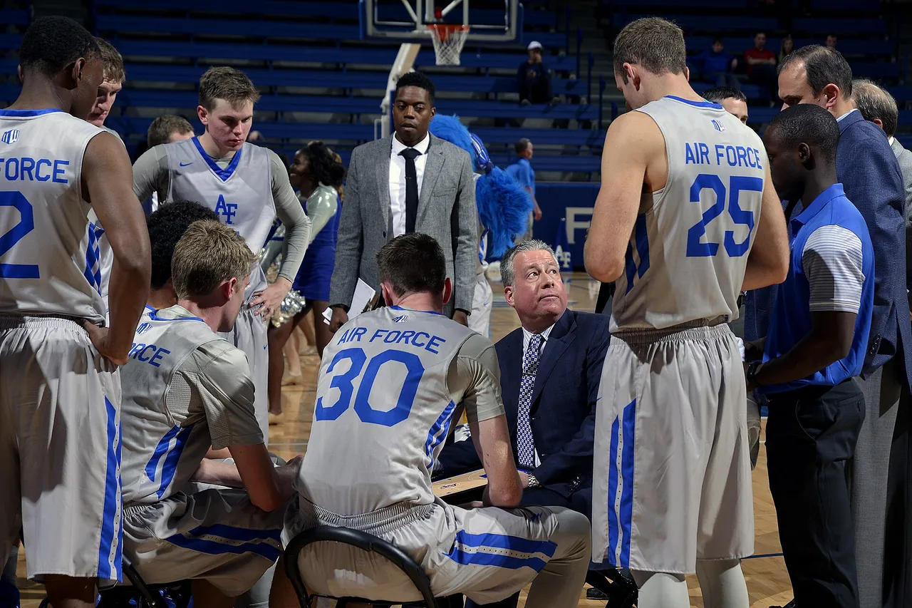 A head coach leads a timeout huddle with his players during a college game
