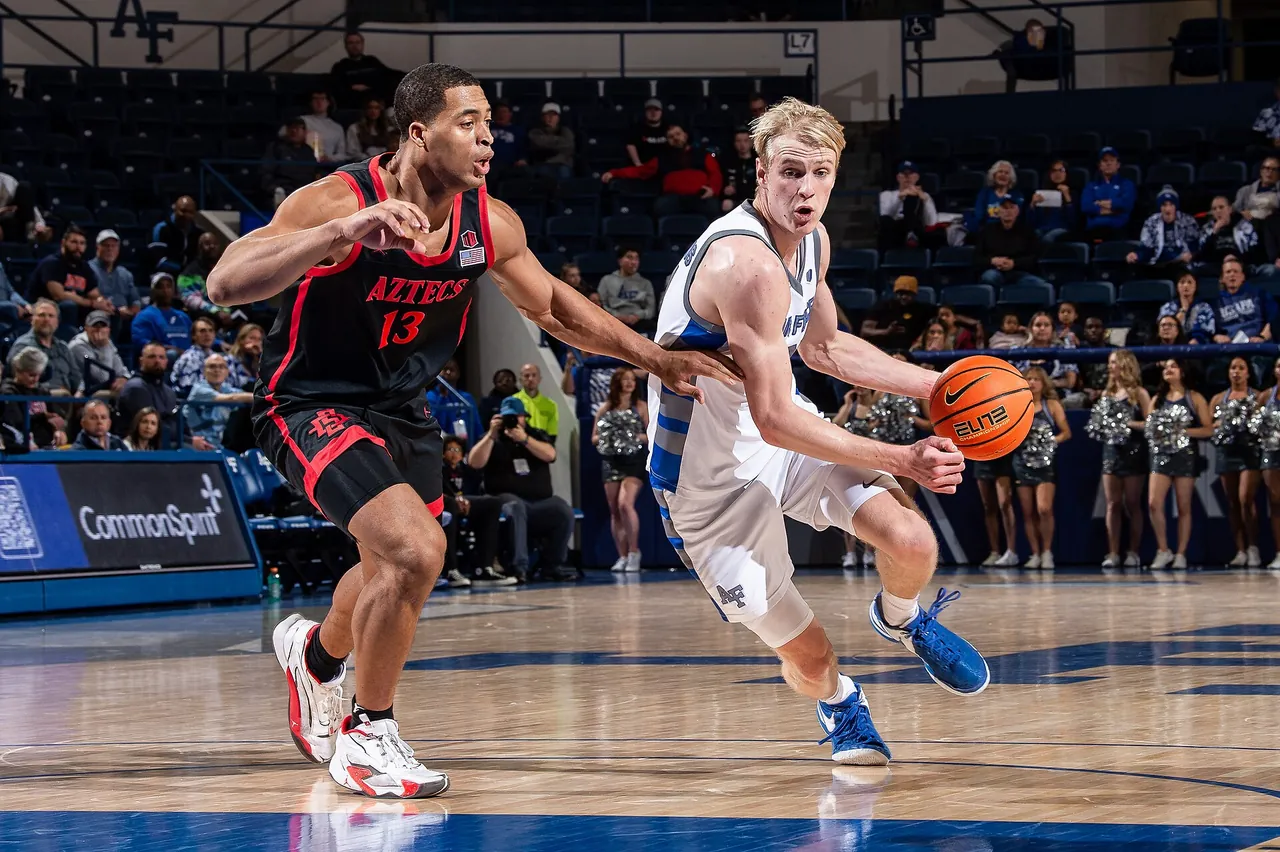 A college guard drives past a defender during a Division I game