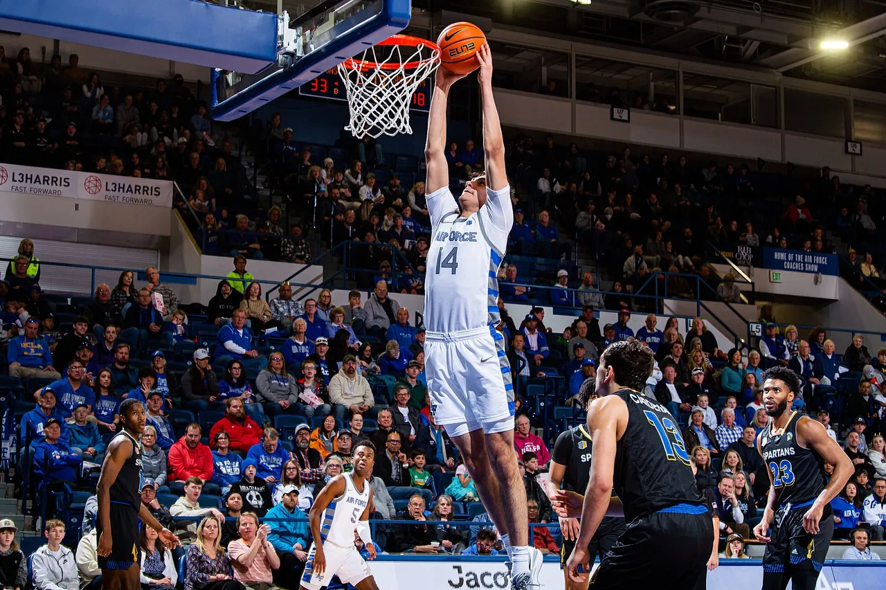 A college player dunks in front of a crowded arena