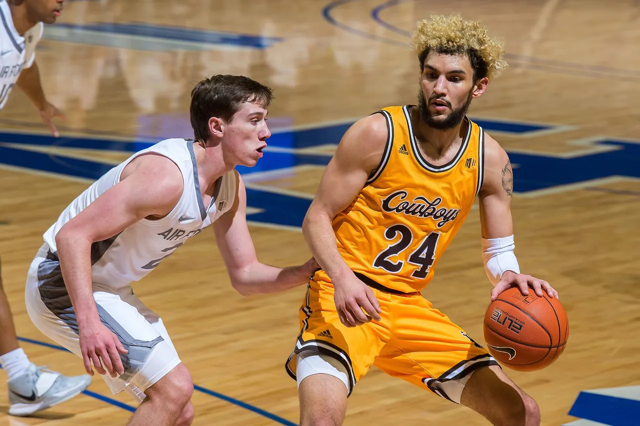 A college forward defends a guard during a Division I game