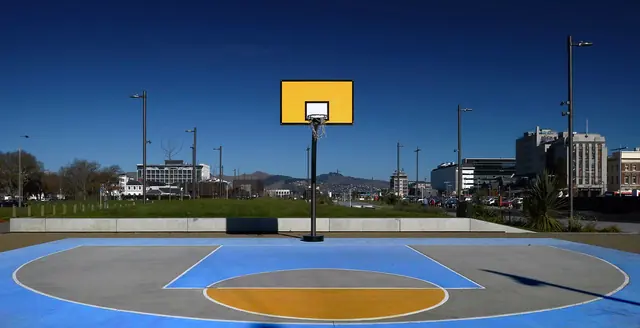 An outdoor court with a yellow backboard and painted lanes