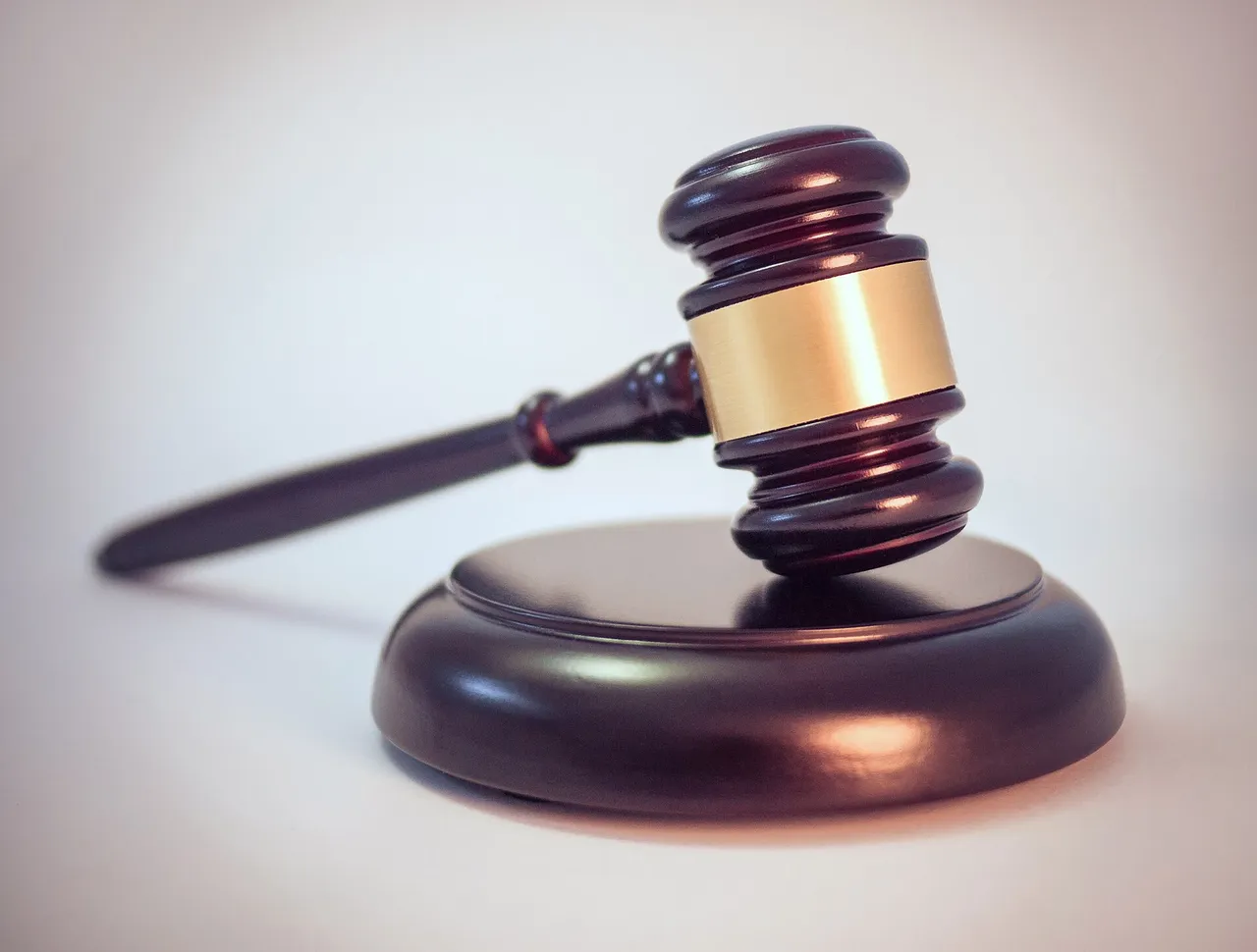 A dark wooden judge's gavel with a brass band resting on its sound block.