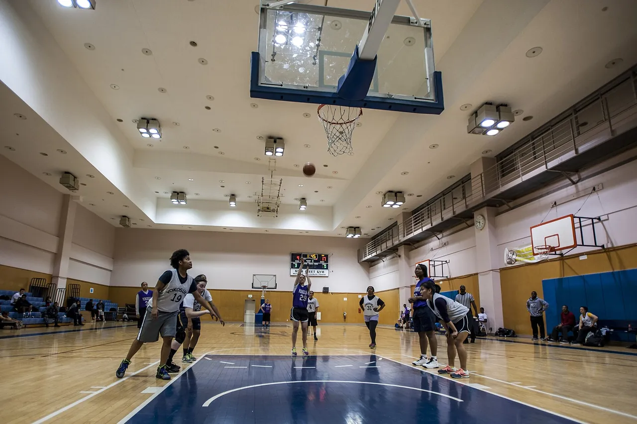 An empty indoor basketball court under gym lights