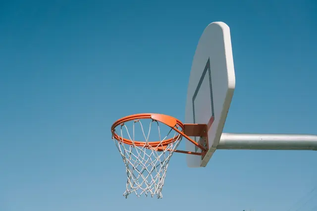An outdoor hoop and white backboard against the sky