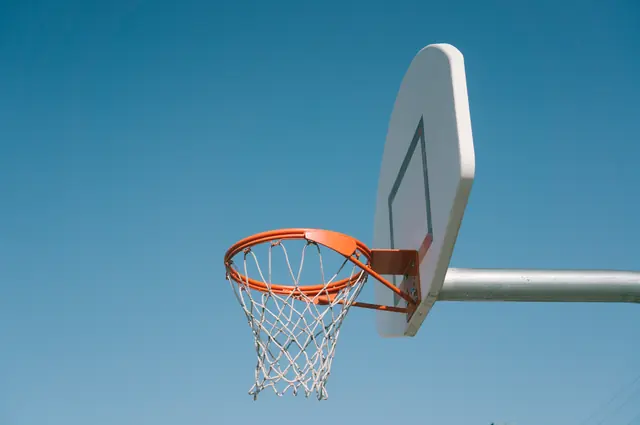 A freestanding hoop and backboard against a clear blue sky