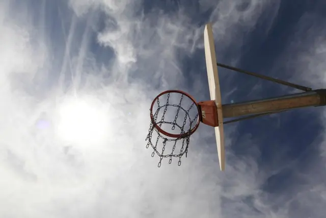 A hoop and backboard against dramatic clouds and sun