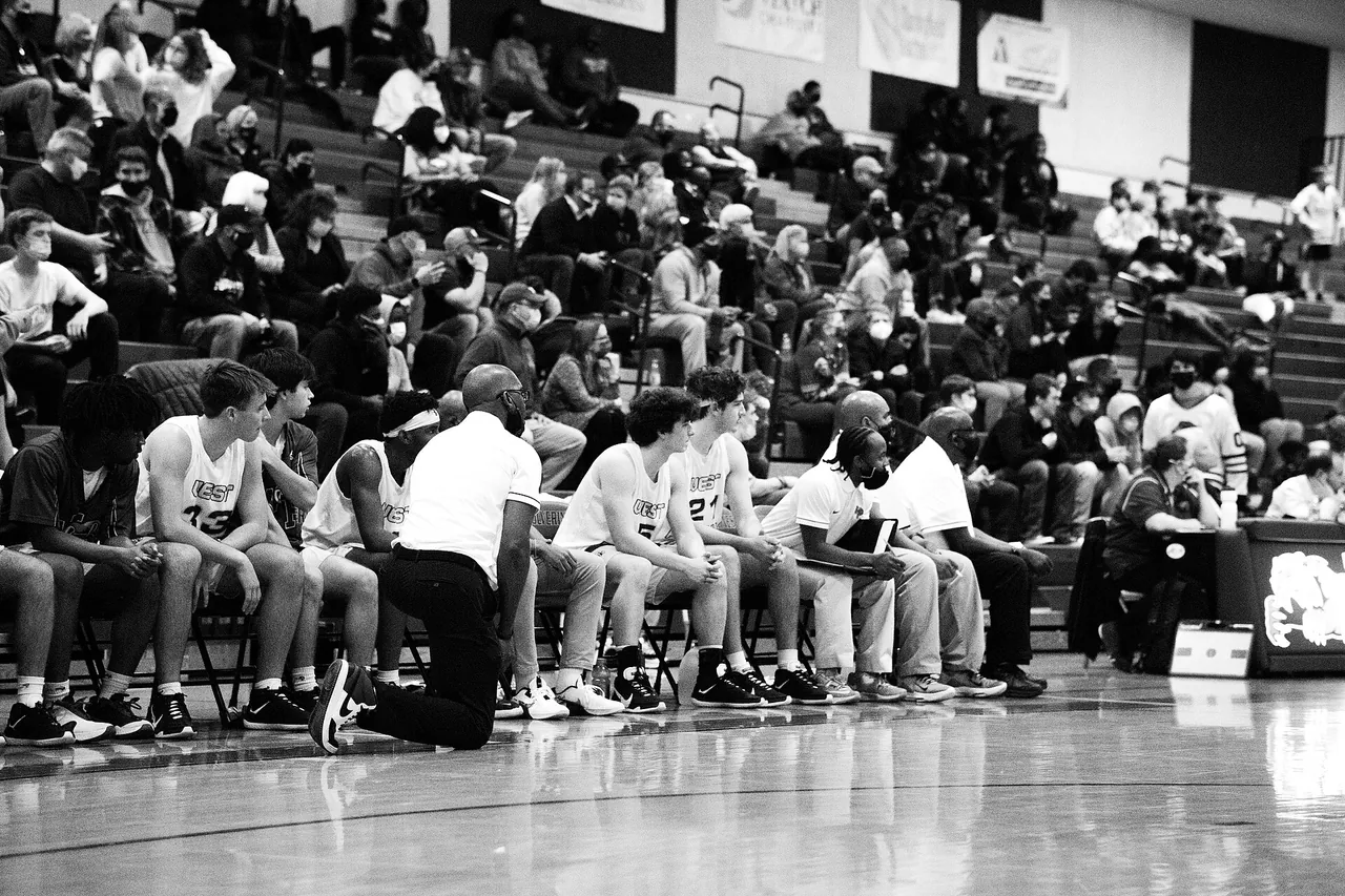 A high school gym full of fans during a varsity game, in black and white