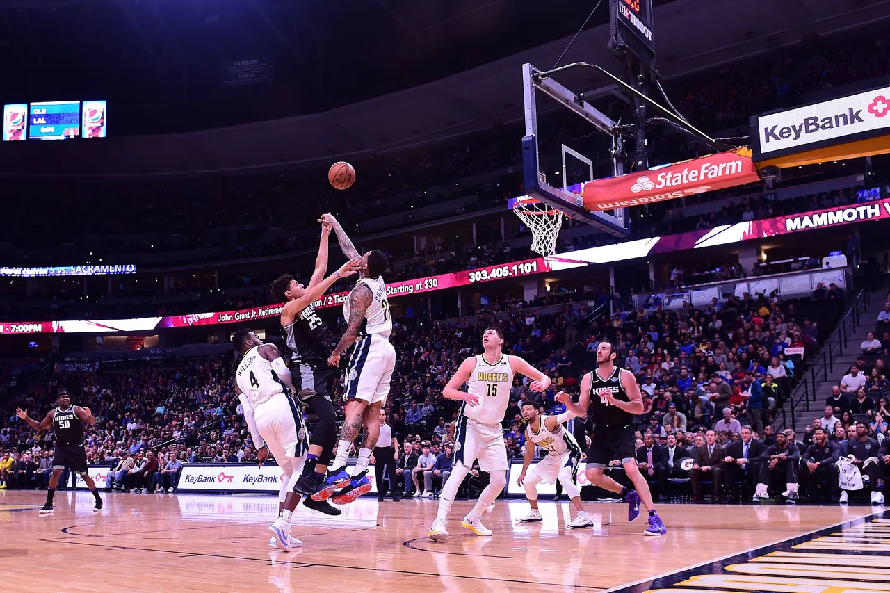 Players contest a rebound during an NBA game under arena lights
