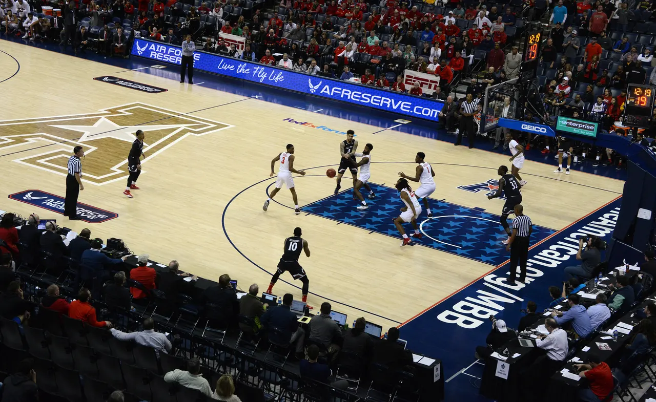 A conference tournament final seen from the upper seats, with laptops lined along press row