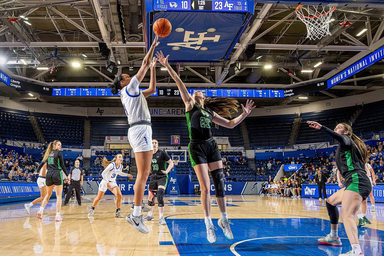 A women's college game in a full arena under bright lights