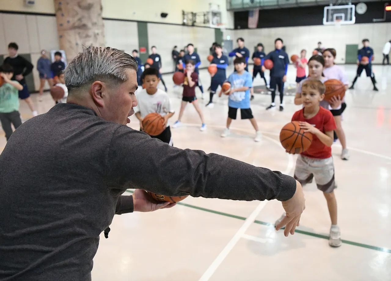 A coach demonstrates a drill to young players at a youth basketball clinic