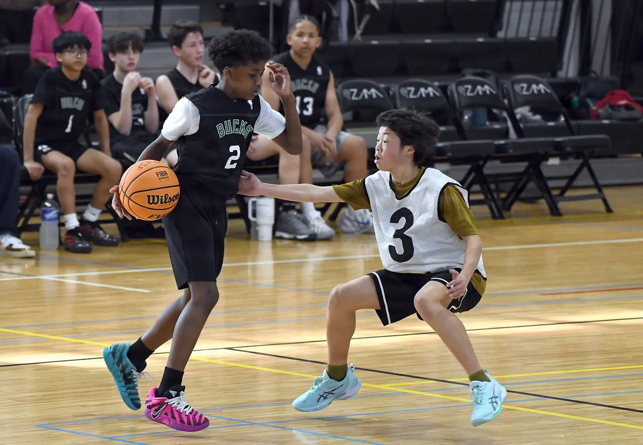 Youth players go one on one during a tournament game in a school gym
