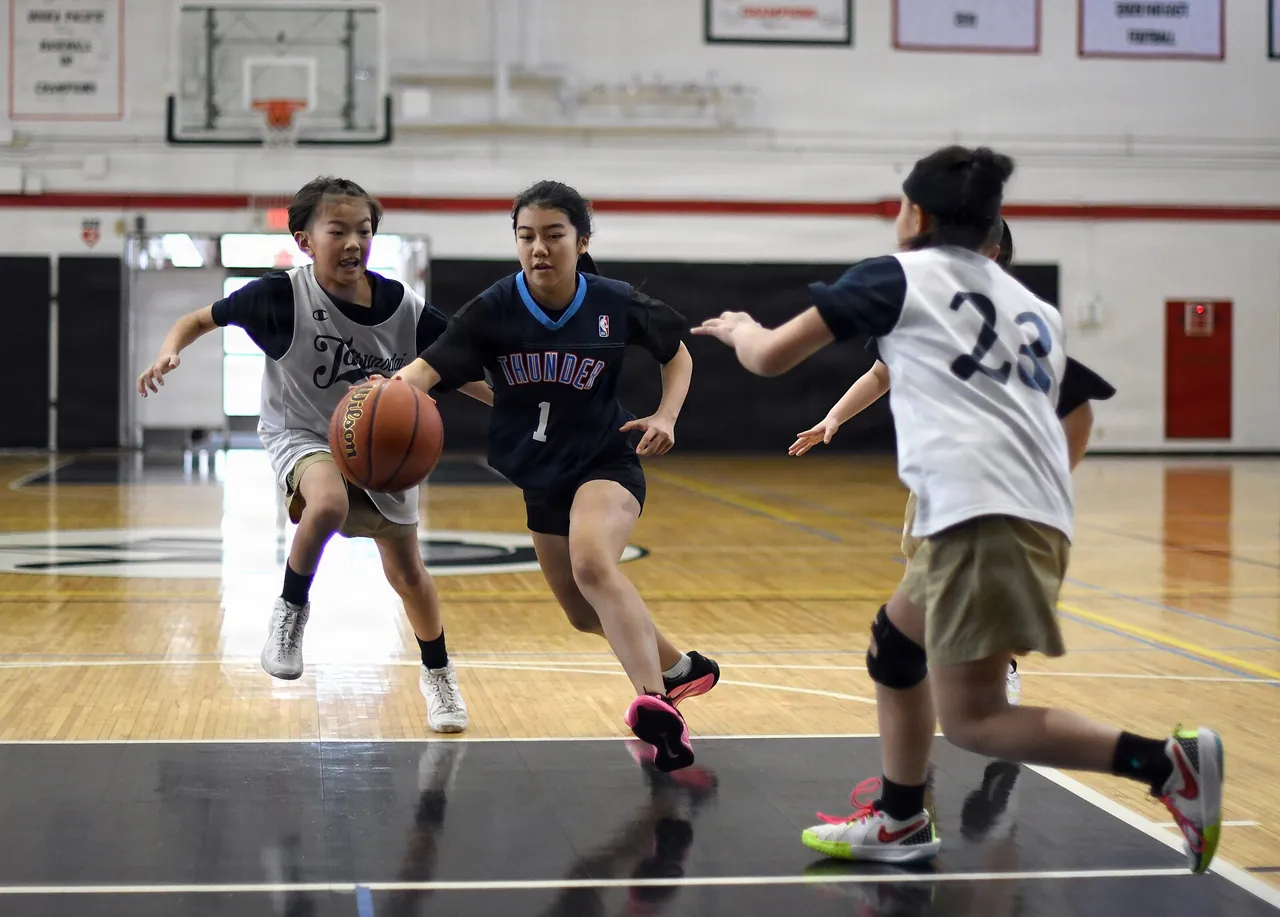 Girls play a youth tournament game in a school gym